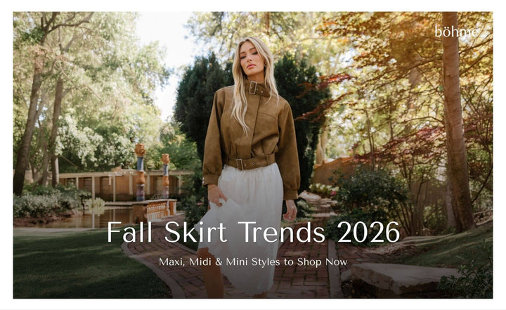 Woman wearing a brown belted jacket and white midi skirt.