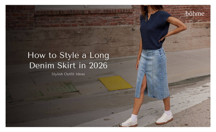 Woman wearing a long denim midi skirt with a front slit, navy knit top, and white sneakers