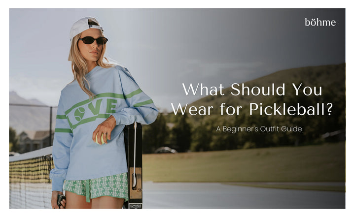 Woman in blue graphic sweatshirt and shorts on a pickleball court