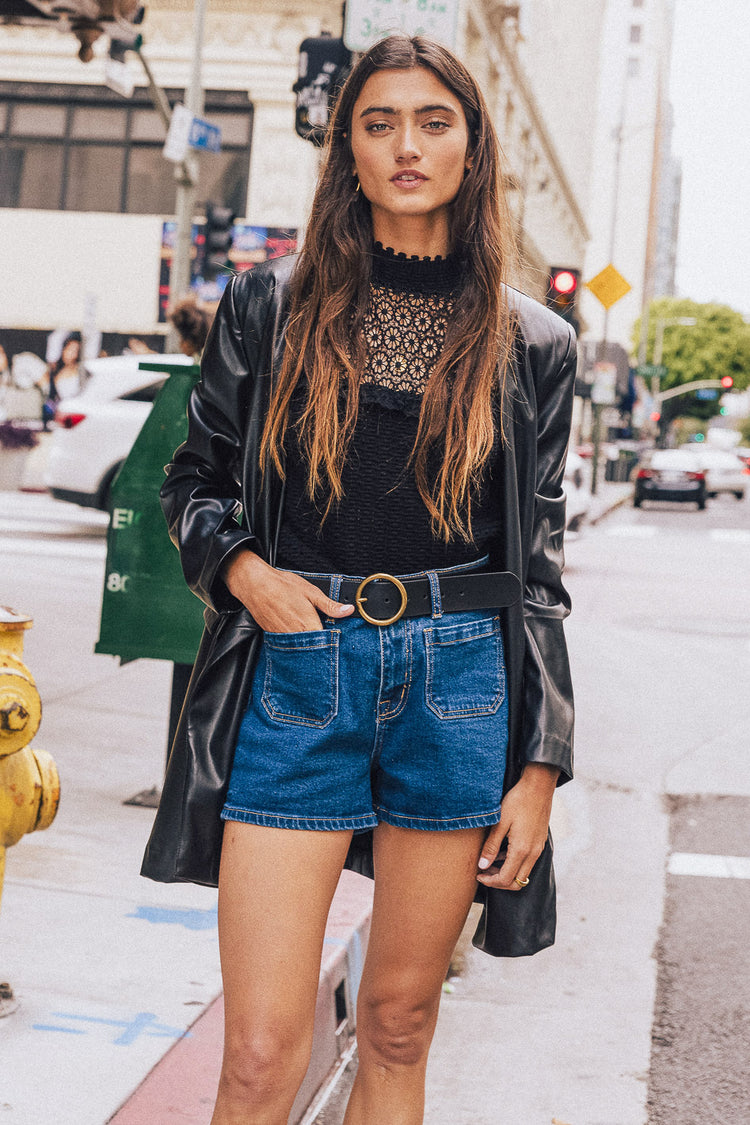 black crochet top with leather jacket, denim shorts and a black belt
