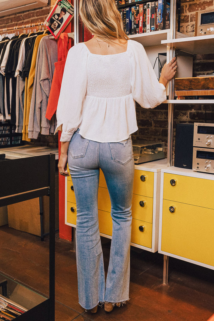 back view of white smocked top and denim jeans