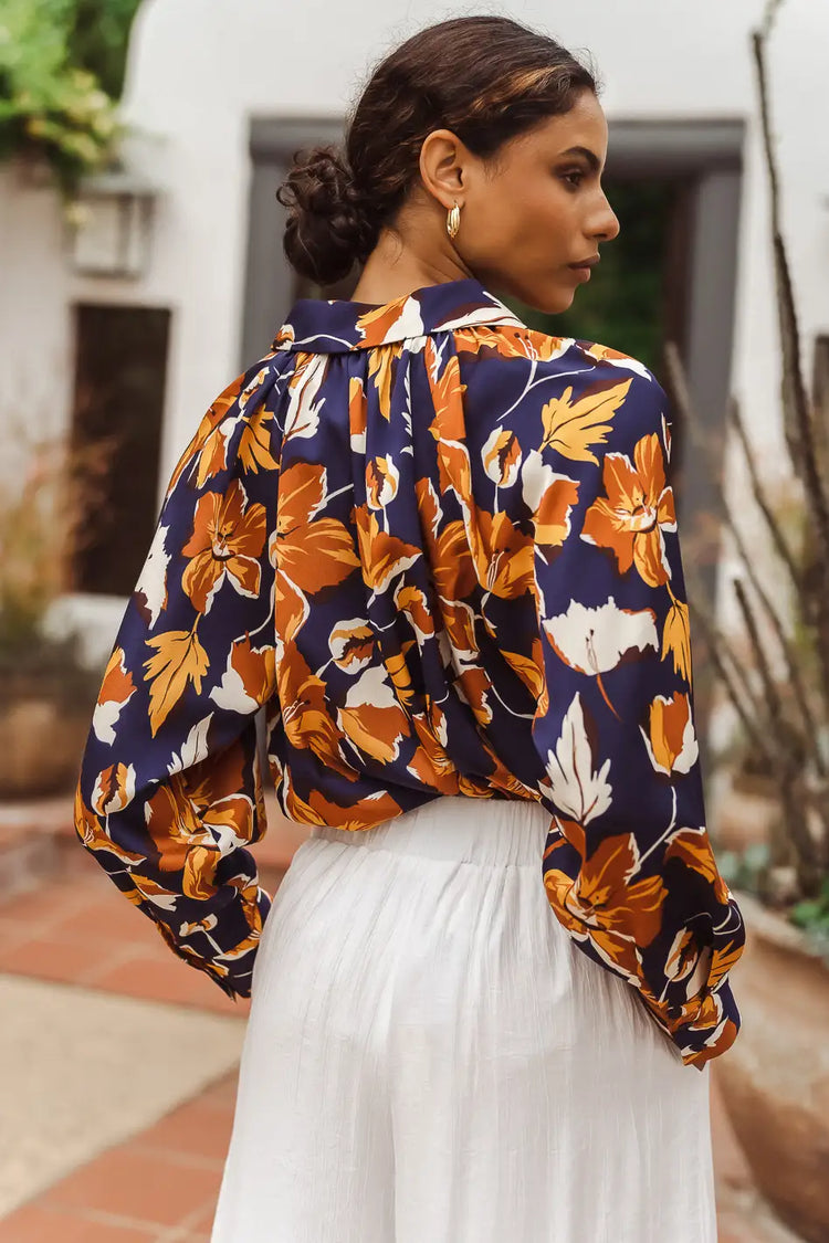back view of floral blouse and white pants
