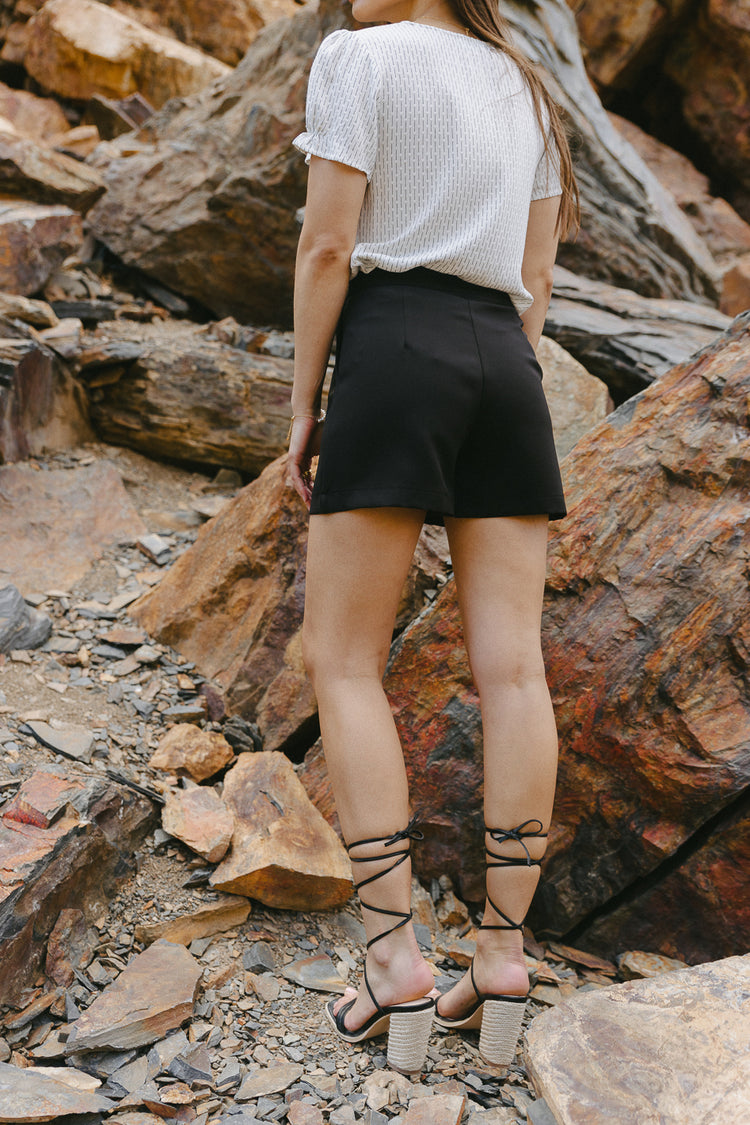 Shorts in black paired with a white blouse 