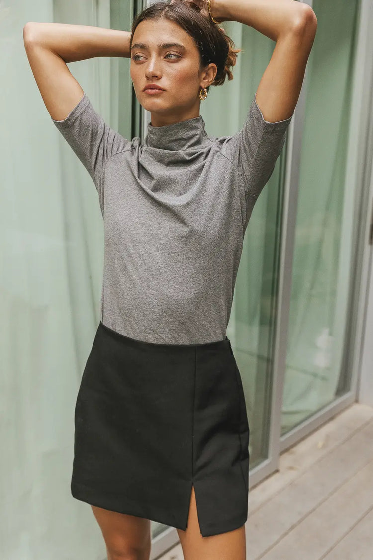 Mock neck top in grey paired with a black  mini skirt 