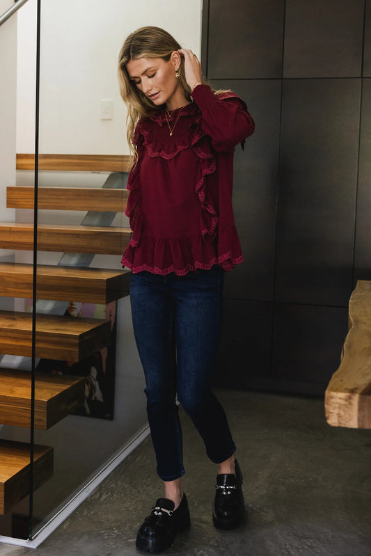 Ruffle blouse in burgundy paired with a dark denim 