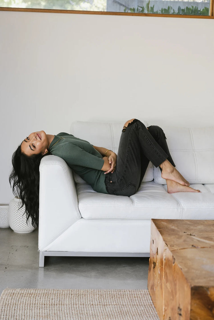 Mock neck sweater top in green paired with a distressed denim pant