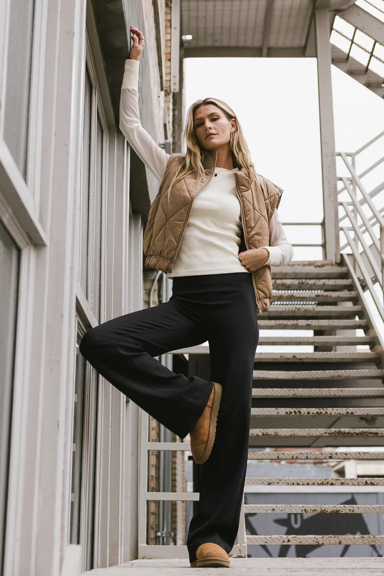 Wide legging in black paired with a cream long sleeves and a camel vest 