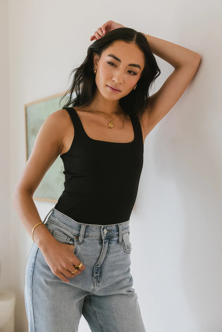 Black bodysuit paired with a light washed denim jeans 