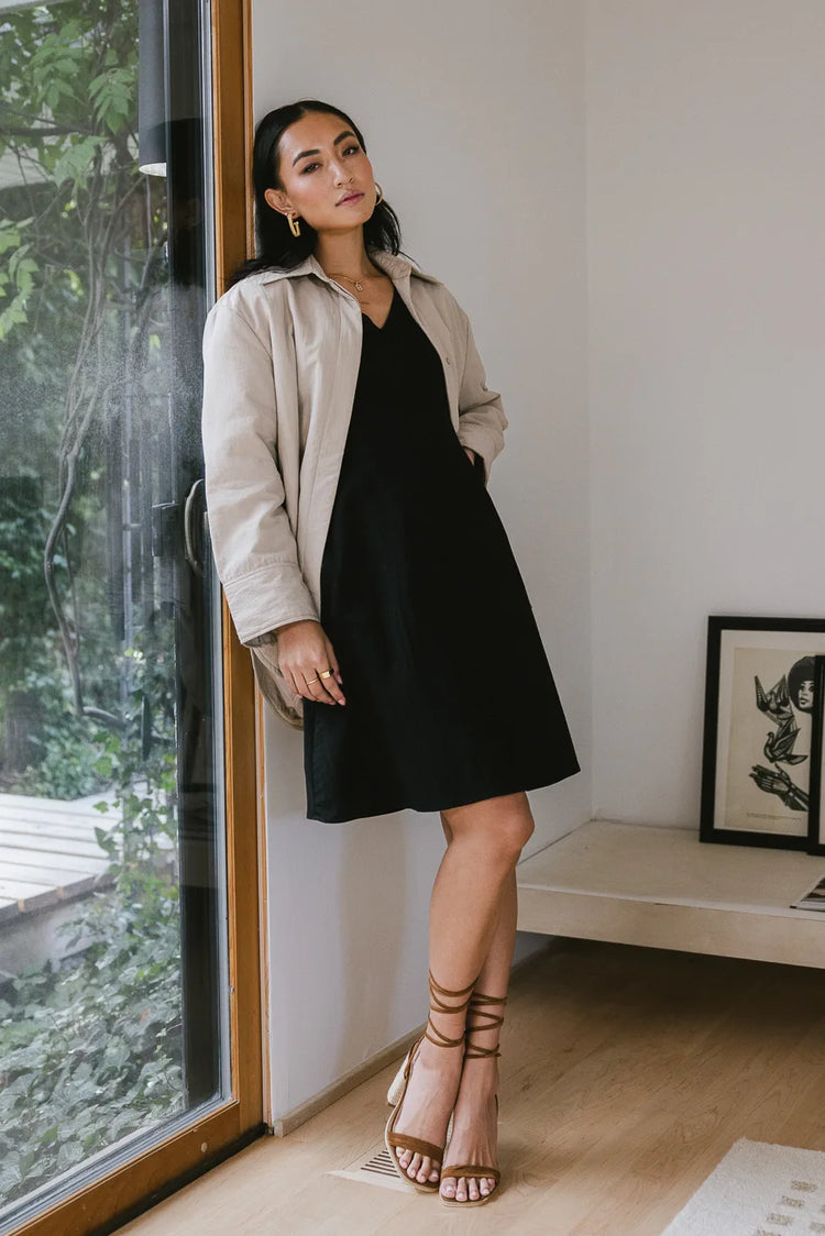 Dress in black paired with a taupe jacket 