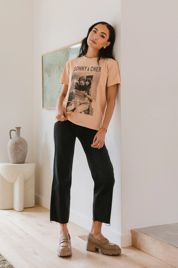 Graphic tee in peach paired with black denim jeans 