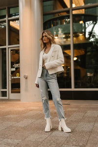 Distressed denim in light washed paired with a cream blazer 