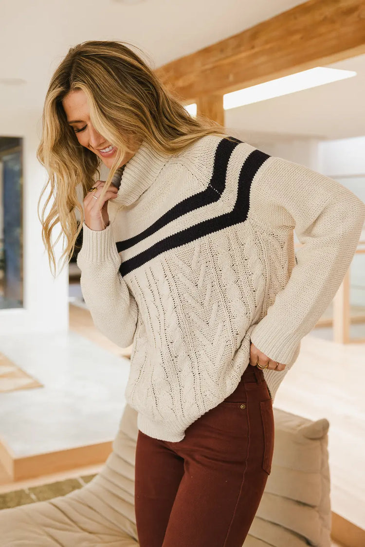 Turtleneck sweater in cream paired with a burgundy jean 