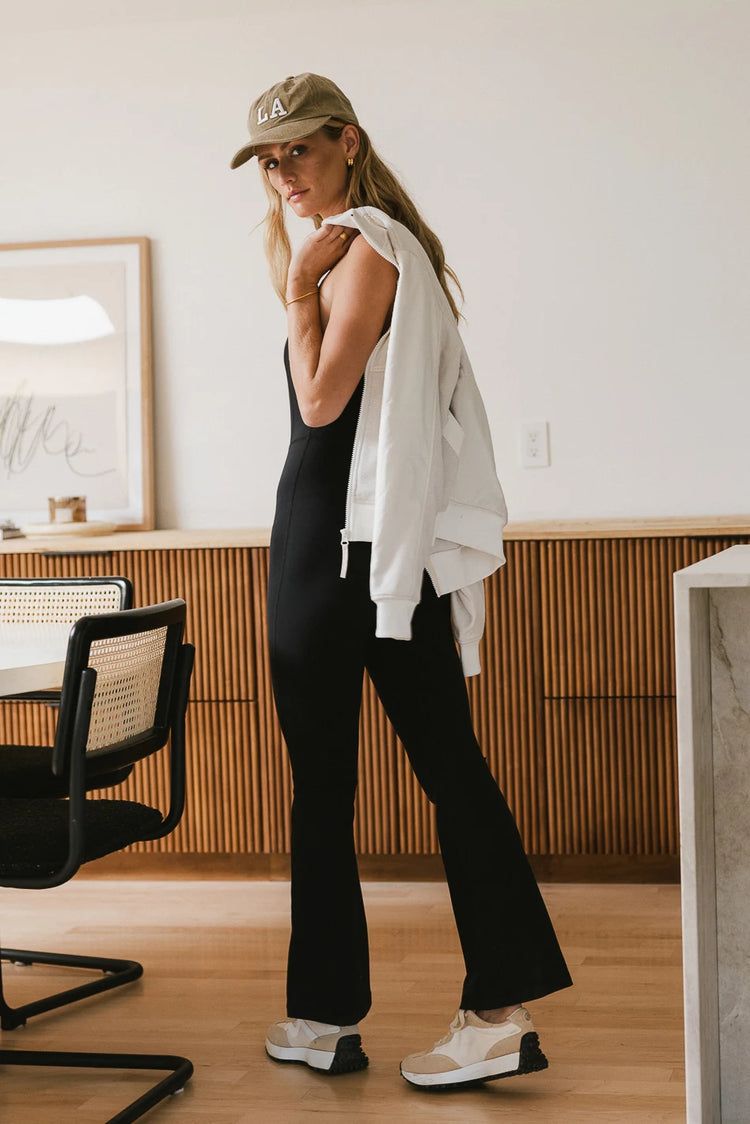 Onesie jumpsuit in black paired with a cream jacket 