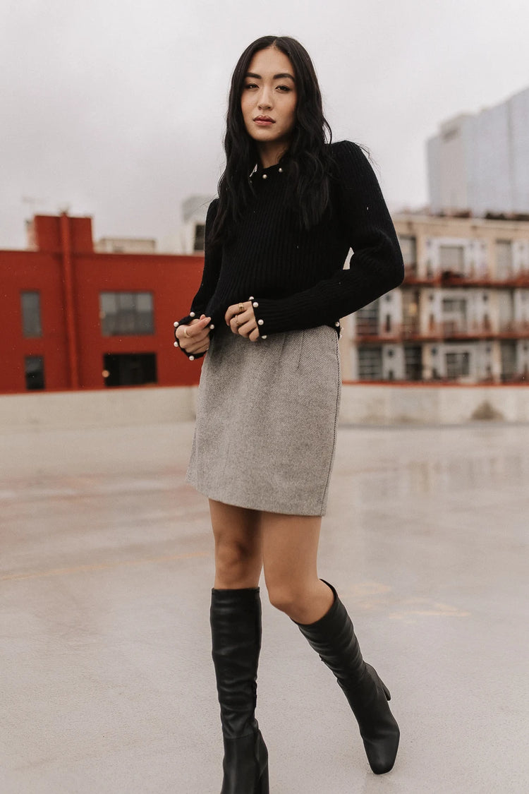 Black sweater paired with a grey mini skirt 