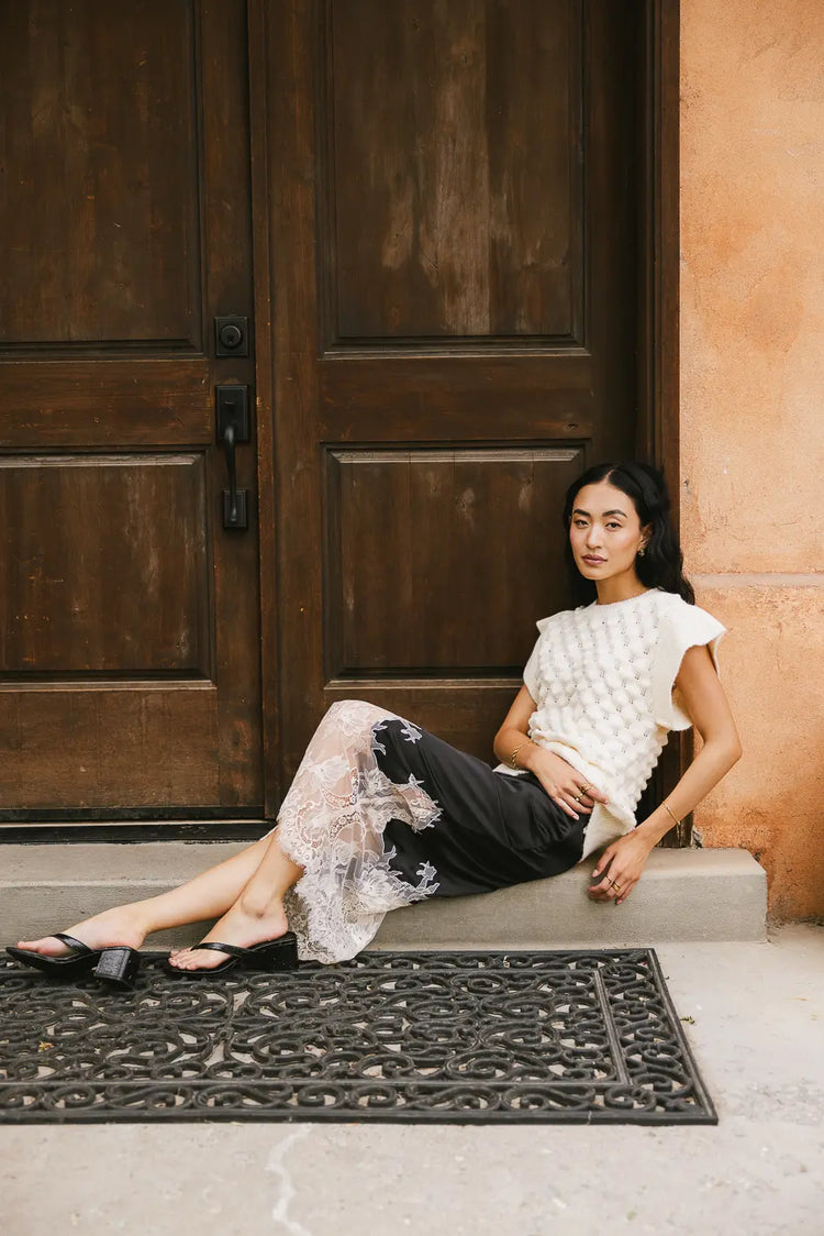 Textures sweater top in ivory paired with a midi black skirt 