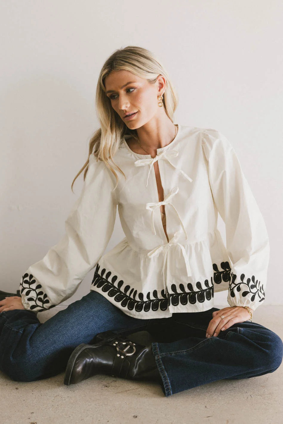 three bow ties on front of cream blouse 