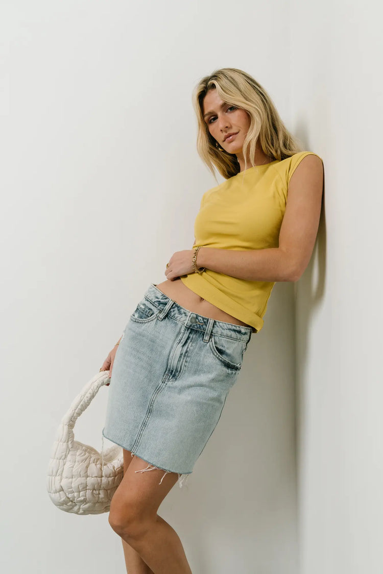 Top in mustard paired with a mini denim skirt 