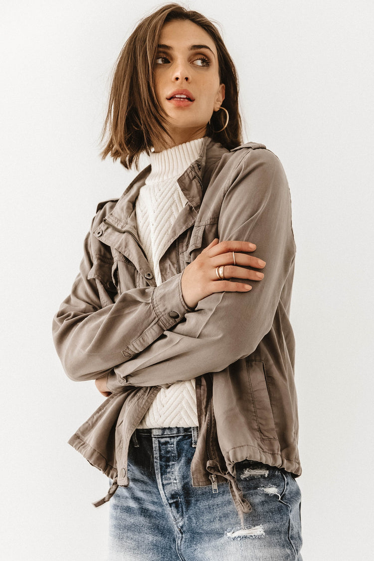 Model wears the Rory Utility Jacket in taupe  over a white mock neck sweater and medium wash jeans.