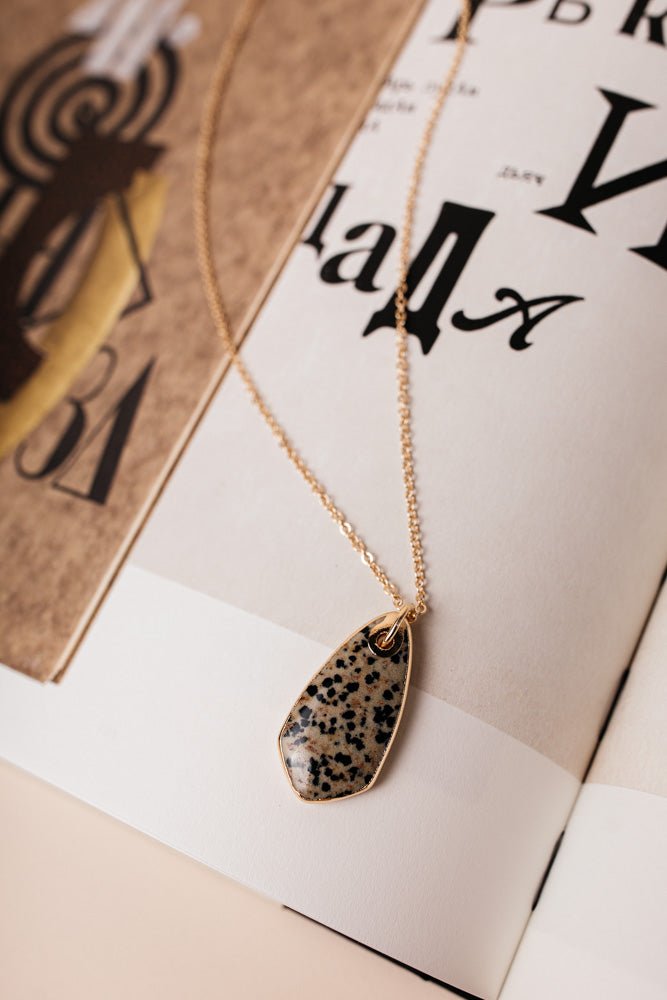 The Monroe Oval Necklace has a thin gold chain and an ovular stone pendant in the middle. It comes in black and marble.