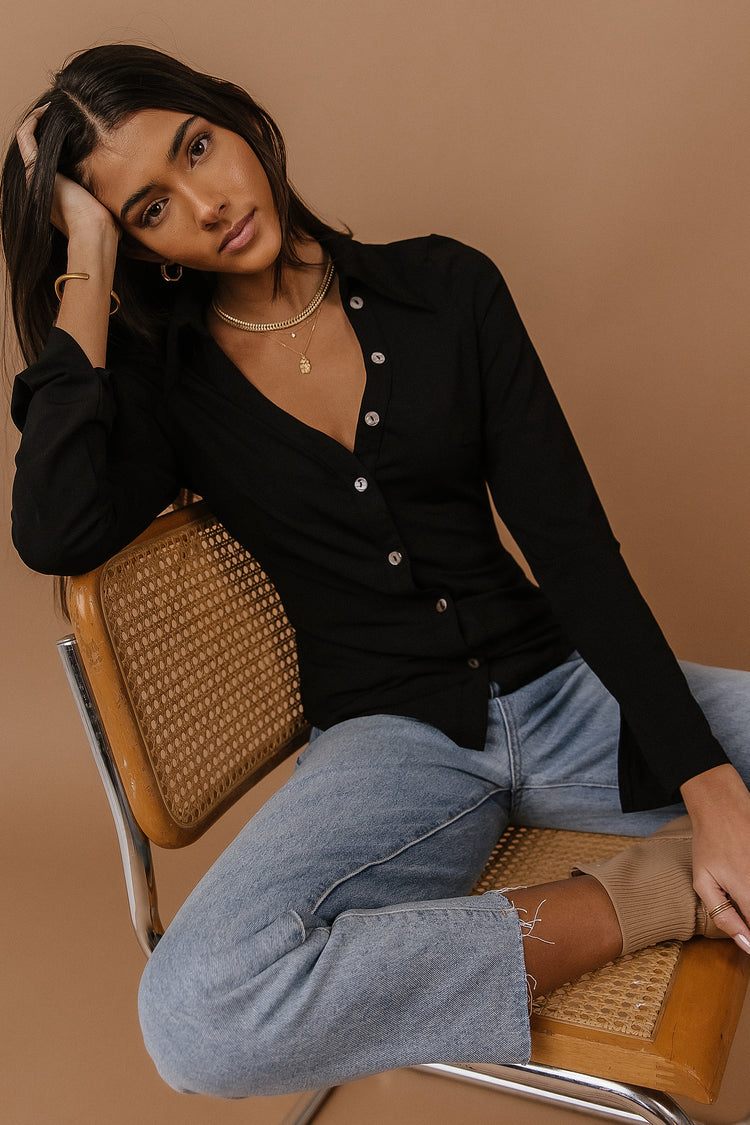 Model wears the Lucine Button Down Top with light wash denim and taupe booties. Top has button detail on one side up to collar and a v-neck.