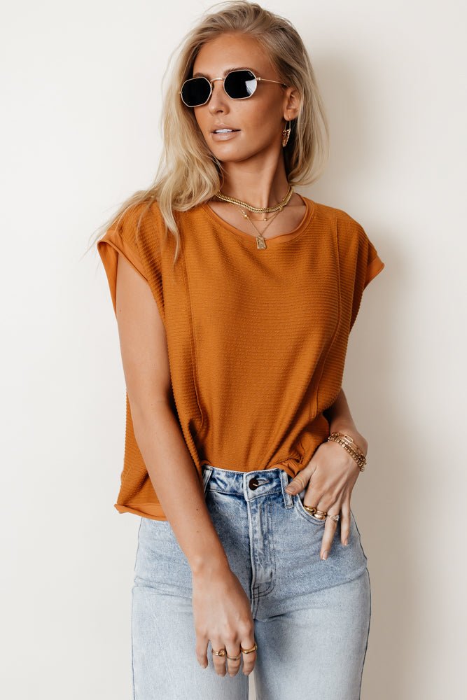 Model wears the Tilly Top in Camel with light wash jeans and black sunglasses. Top has cap sleeves, oversized fit, and crew neck.