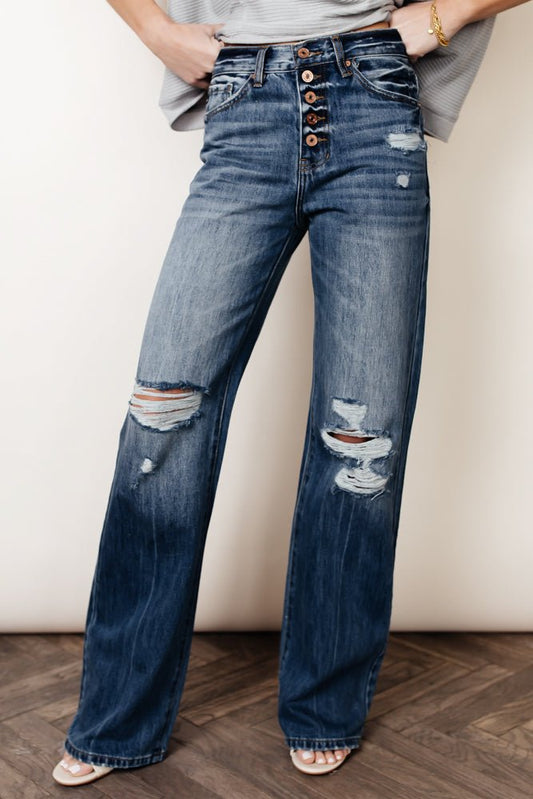 A woman wearing high rise wide leg denim jeans with her hands on her hips.