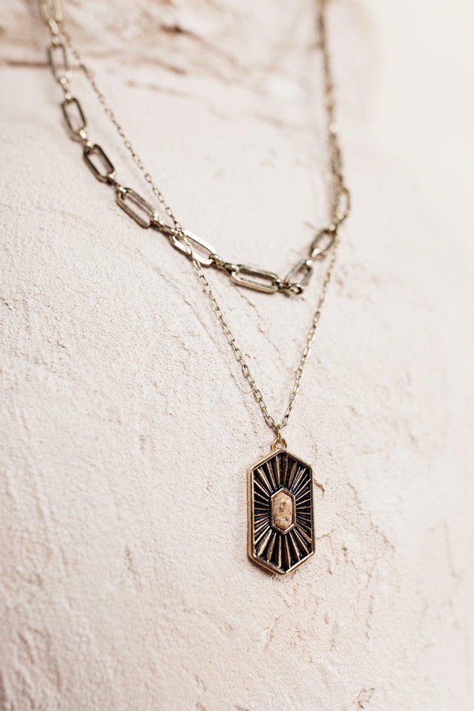 The Liliana Necklace has two chains, one small gold chain with a hexagonal pendant and one larger chain link layer.