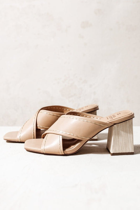 The Jade Heels in Nude have wooden thick block heels and faux leather criss cross straps with beige stitching. Sandals have square toe.