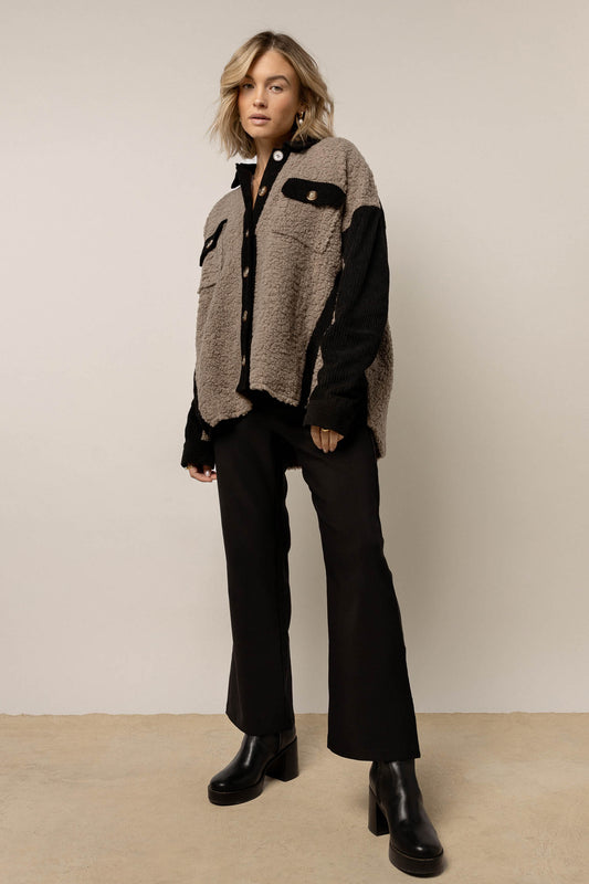 model wearing grey Sherpa and black corduroy  jacket with collar paired with black pants and black boots