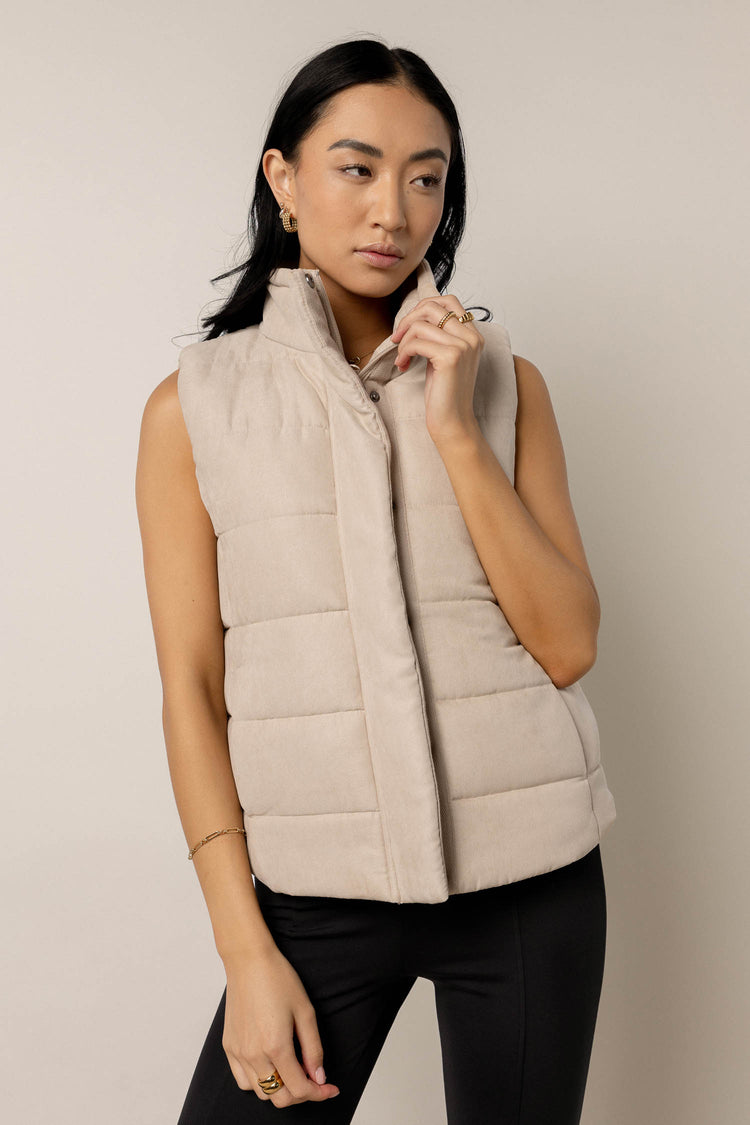model wearing beige puffer vest paired with black pants