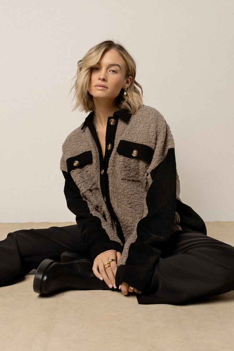 model wearing grey Sherpa and black corduroy jacket with collar paired with black pants and black boots