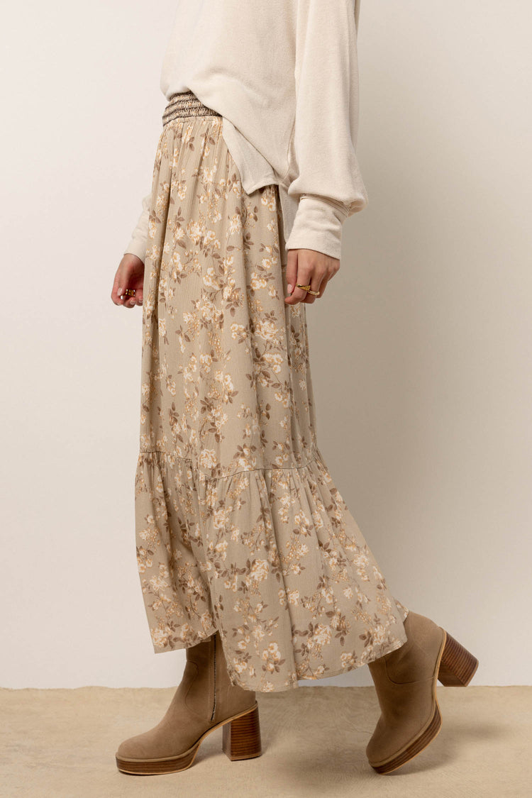 model wearing sage floral maxi skirt paired with tan boots and cream top