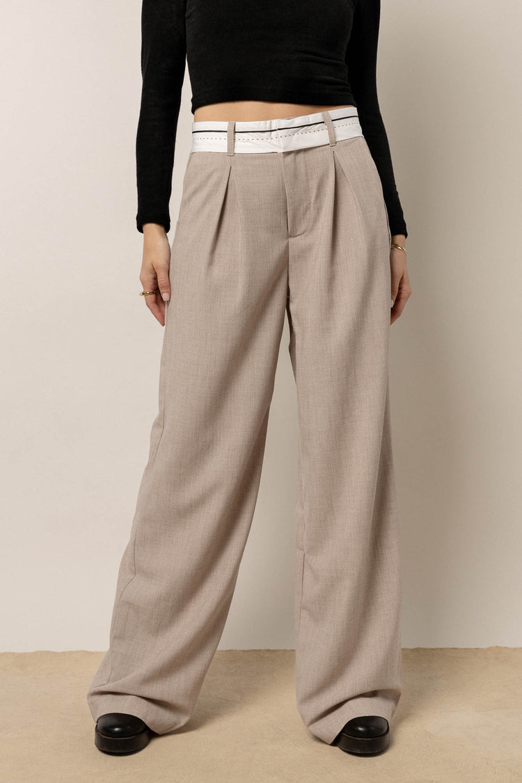 model wearing taupe wide leg trousers with white waist band paired with black cropped top and black boots 