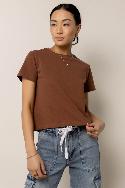 model wearing short sleeve brown baby tee paired with medium washed denim