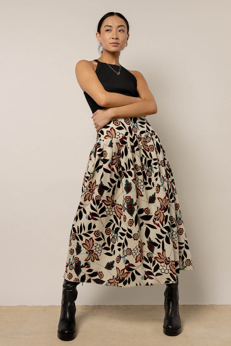 model wearing cream midi floral skirt paired with tall black boots and black tank top