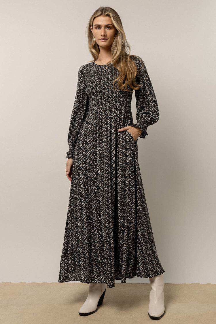 model is wearing floral print maxi dress with  long sleeves and white boots