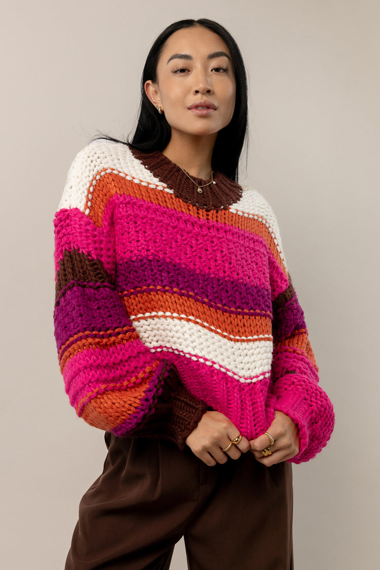 model is wearing a long sleeve striped knitted sweater with brown pants