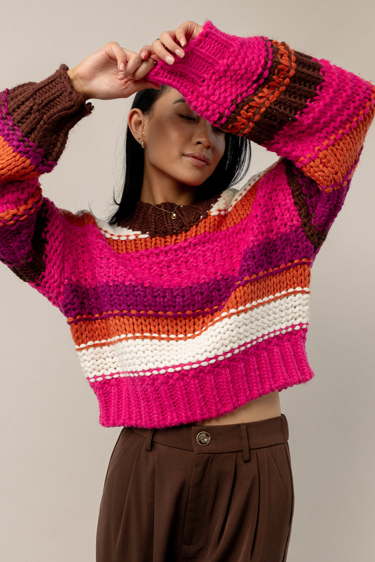 model is wearing a long sleeve striped knitted sweater with brown pants