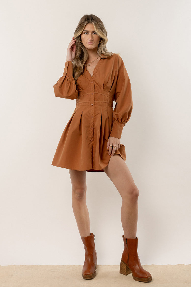 model is wearing long sleeve mini dress with brown boots