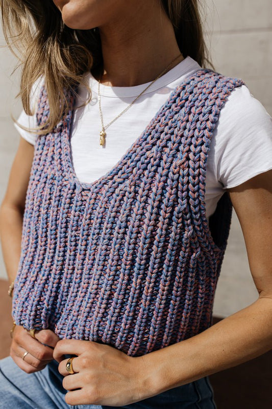 A woman in a cropped sweater vest.