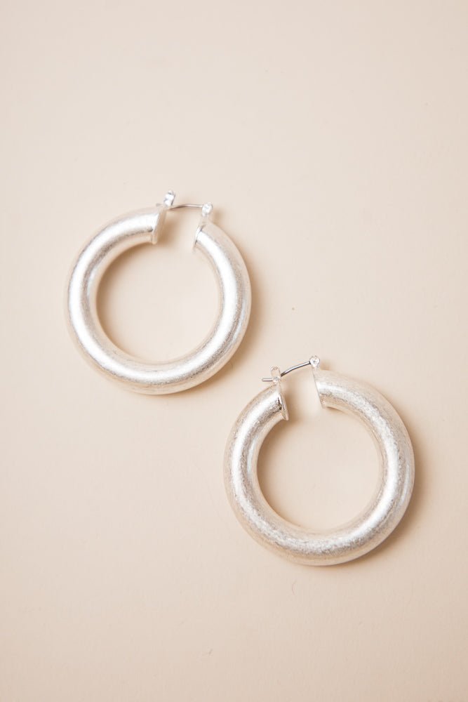The Salome Hoop Earrings in Silver have thick silver hoops and a hinge hoop closure.