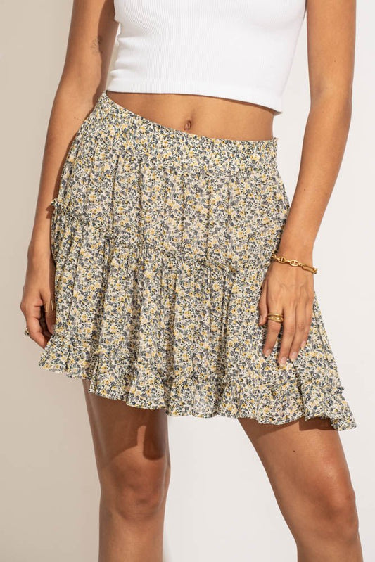 A woman in a white top wearing a floral mini skirt.