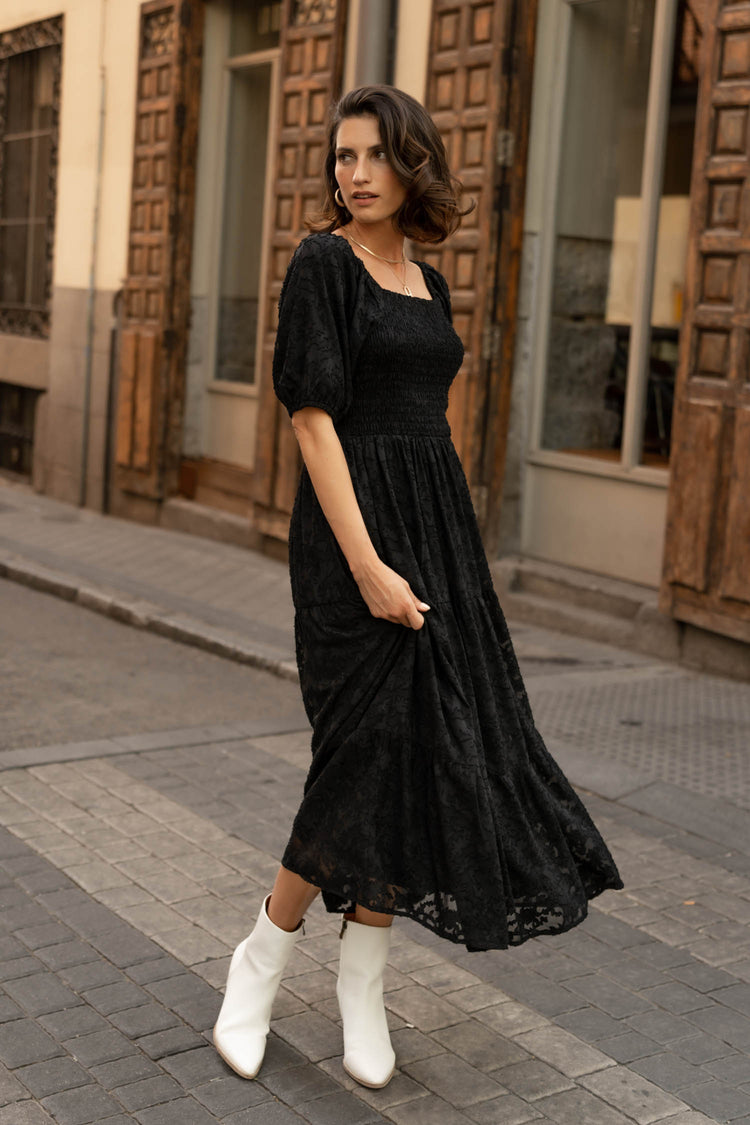 model wearing black short sleeved midi dress paired with white boots