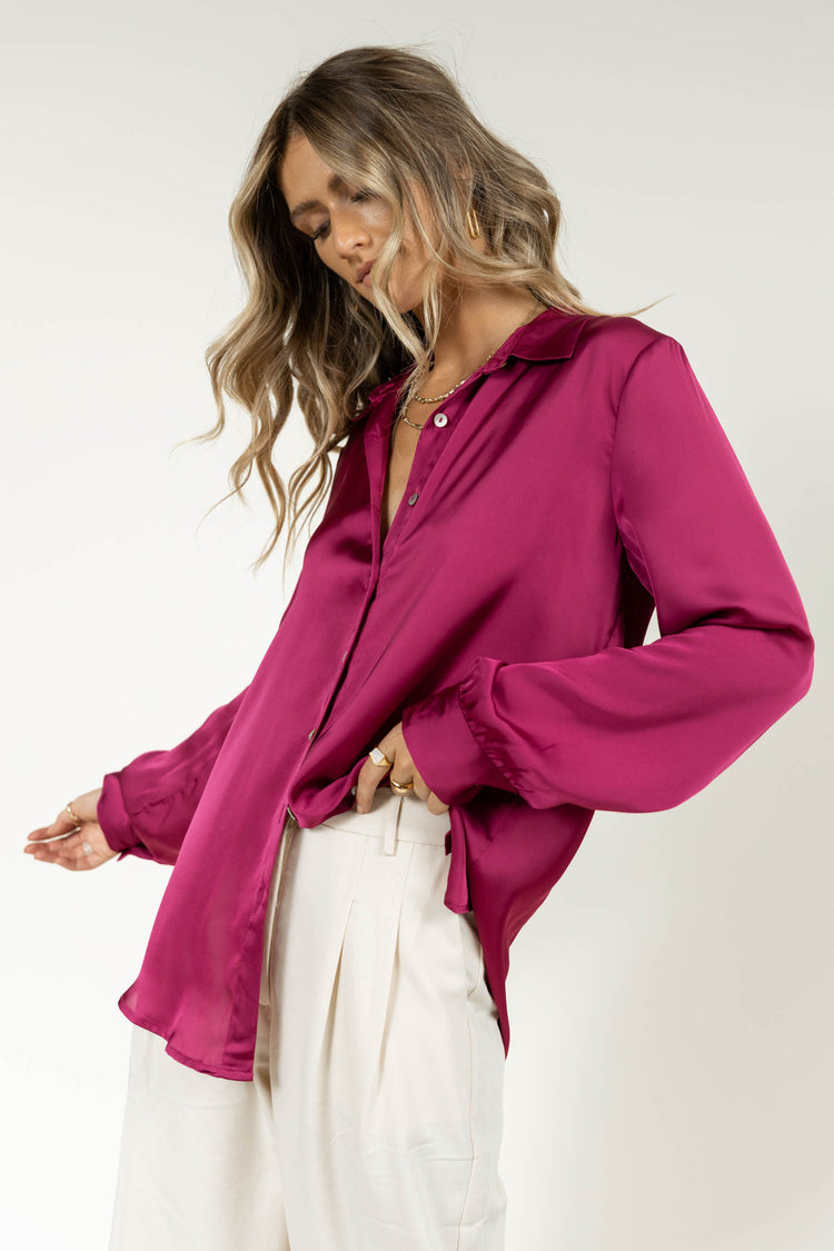 Model wearing magenta silk blouse with cream trousers