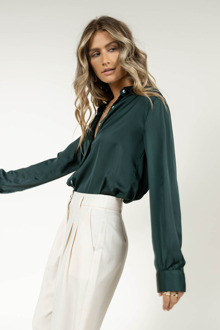 Model wearing emerald button down with cream trousers