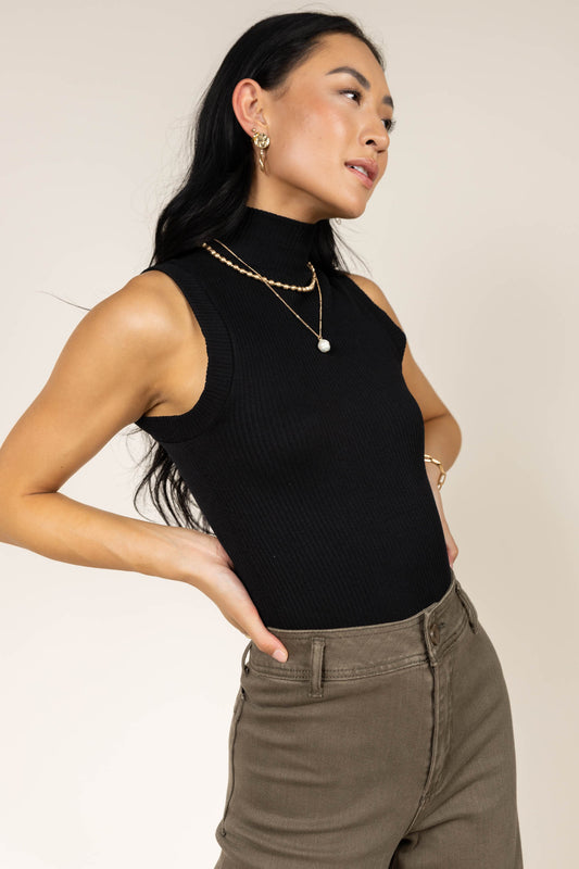 Model wearing black ribbed turtle neck tank top paired with olive wide leg pants
