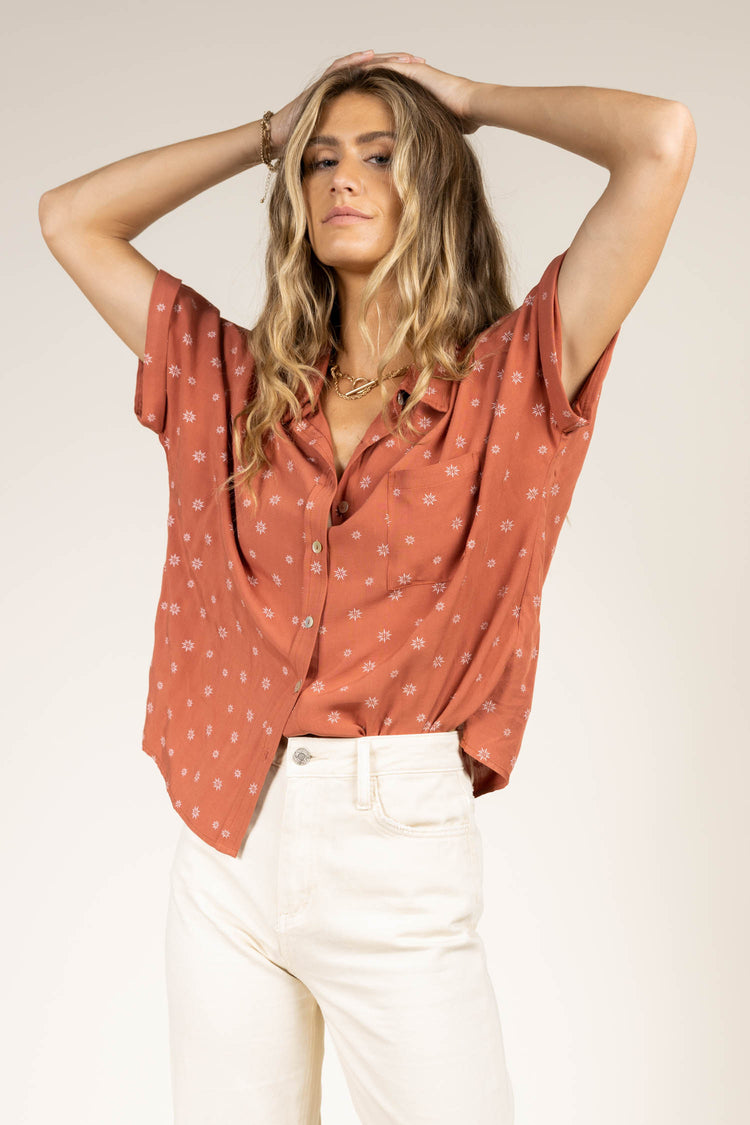Rust button down top with white flowers paired with cream distressed denim