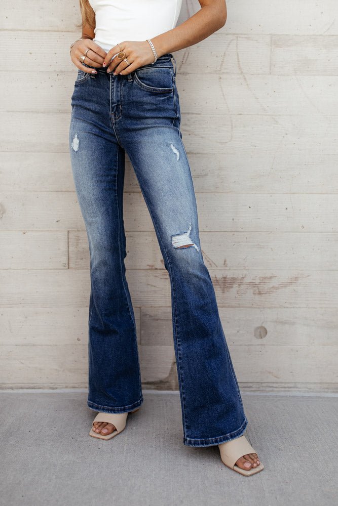 woman standing in ripped blue denim flare jeans