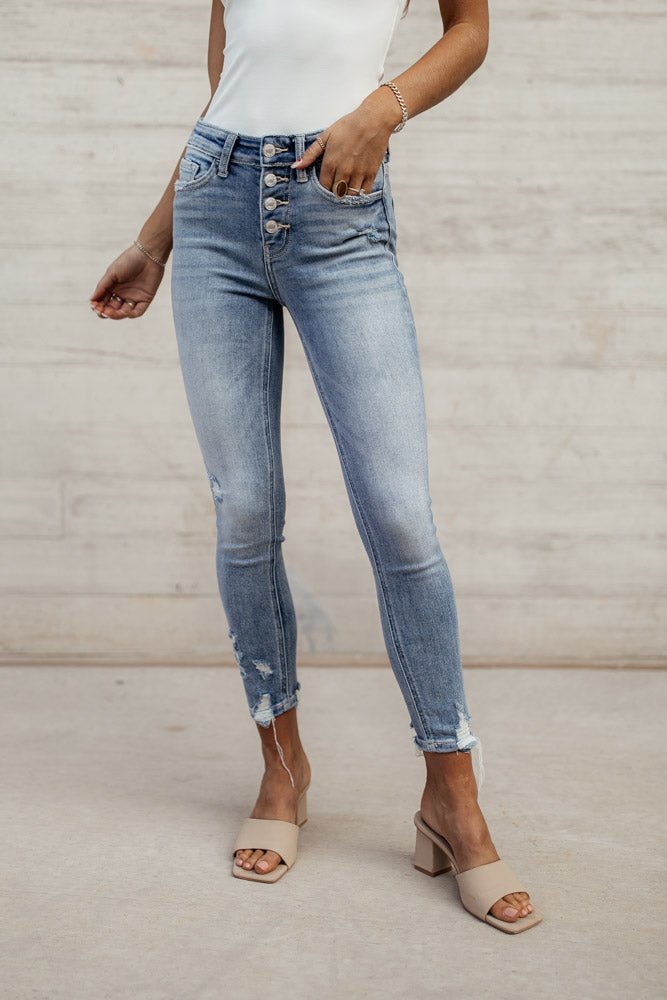 Model is shown from the waist down wearing light-wash blue skinny jeans featuring a button fly closure.