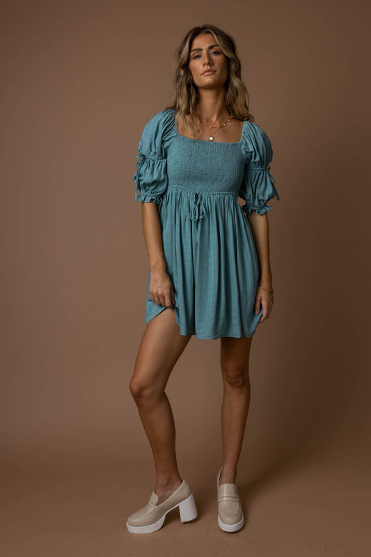 model wearing blue mini dress with smocked top paired with cream loafers